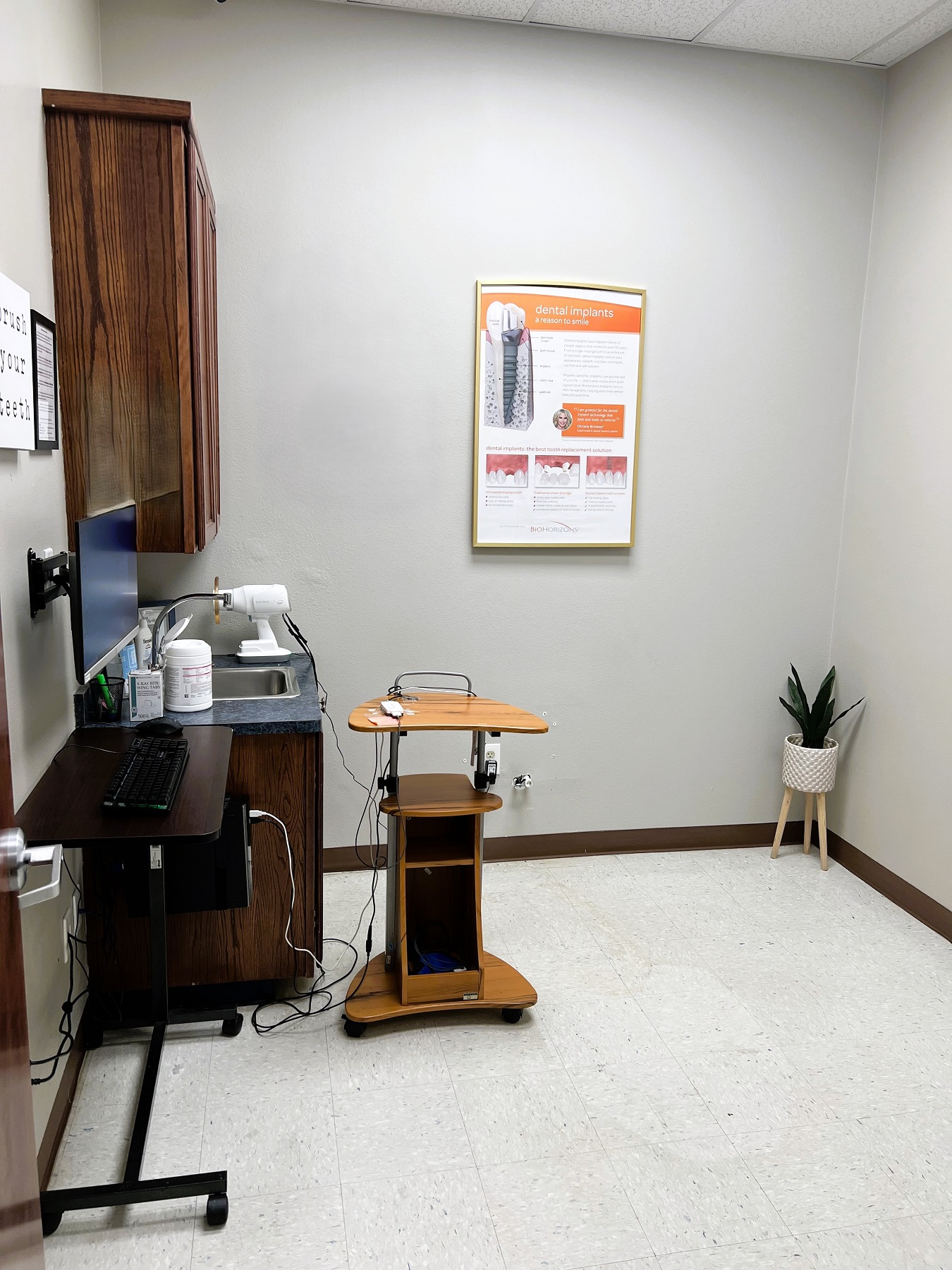 Light colored walls with dark baseboards and white, large tile flooring. Dark stained cabinetry with a matching rolling cart