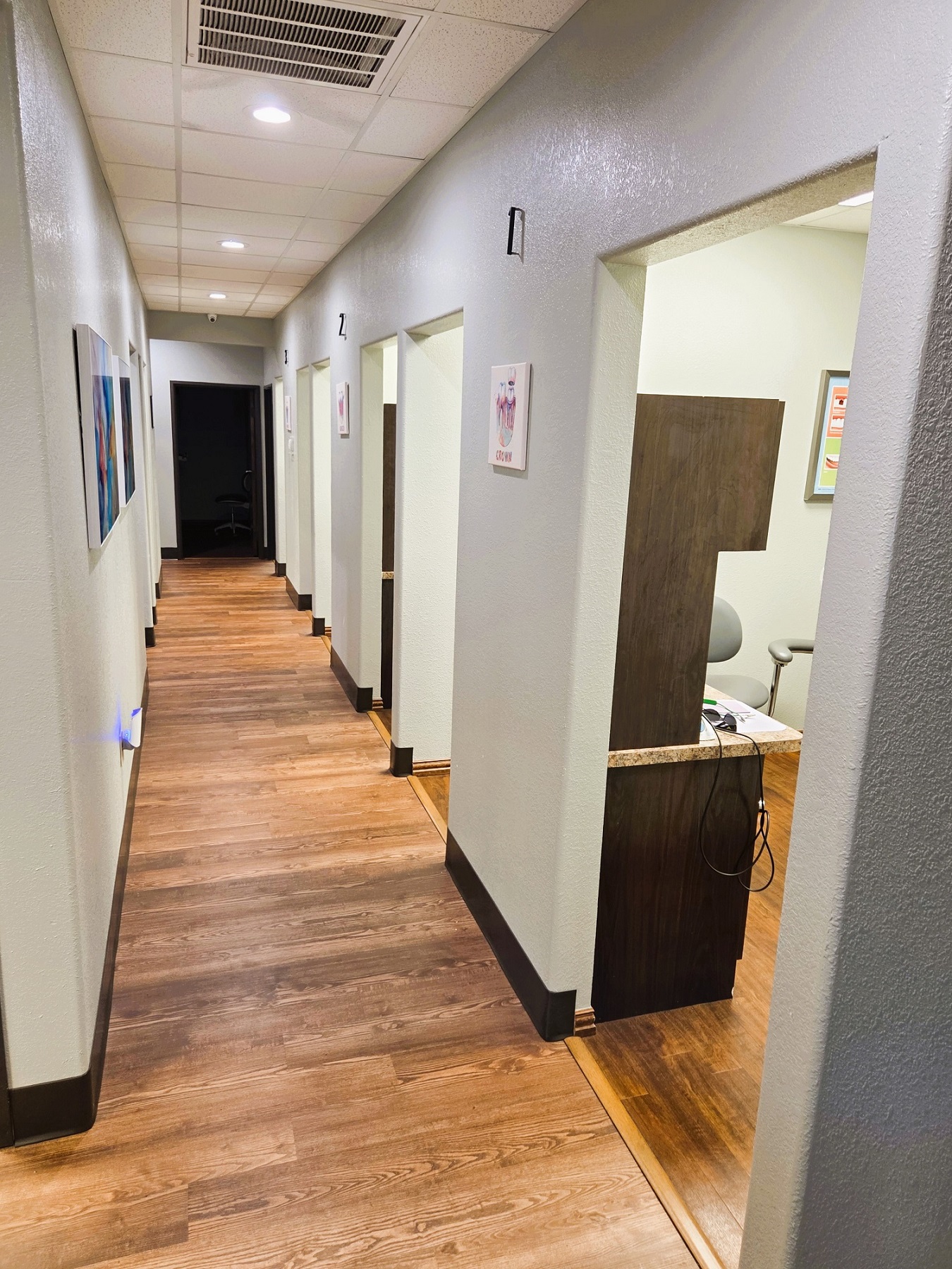 Light grey walls with dark baseboards and dark stained wood-look vinyl flooring. Doorways to the different rooms of the practice.