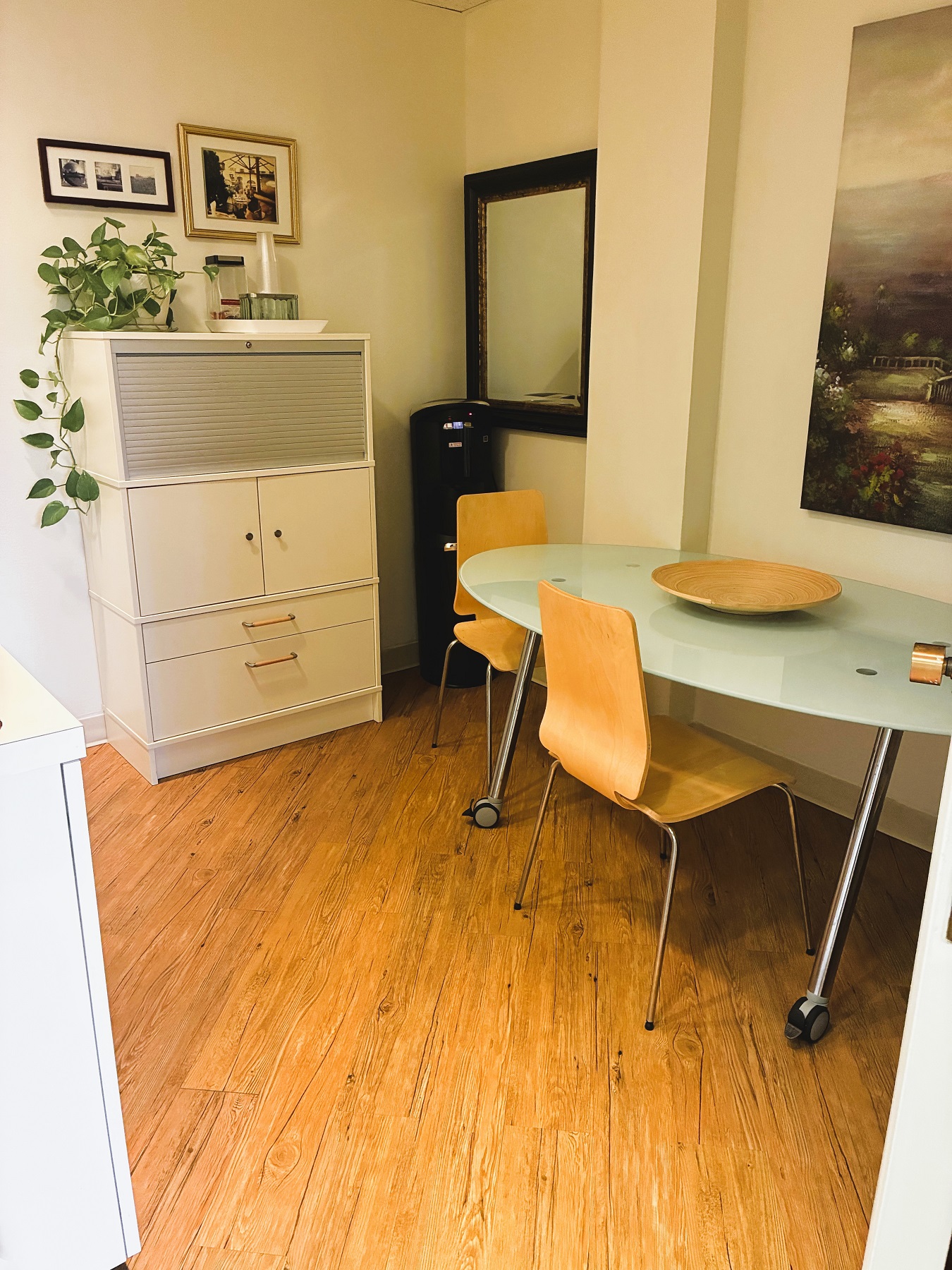 Light walls and hardwood floors with white cabinetry and a light blue oval table surrounded by mid-century modern chairs.