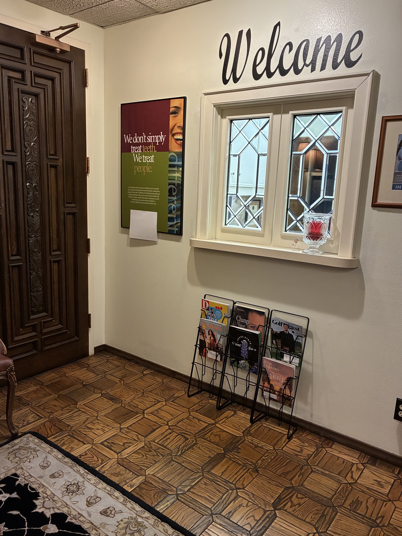 Light walls with dark baseboards and parquet flooring. A small magazine rack leans against the wall below the reception window.