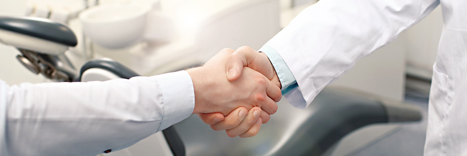 A dental practice owner shakes hand her with new dental associate.